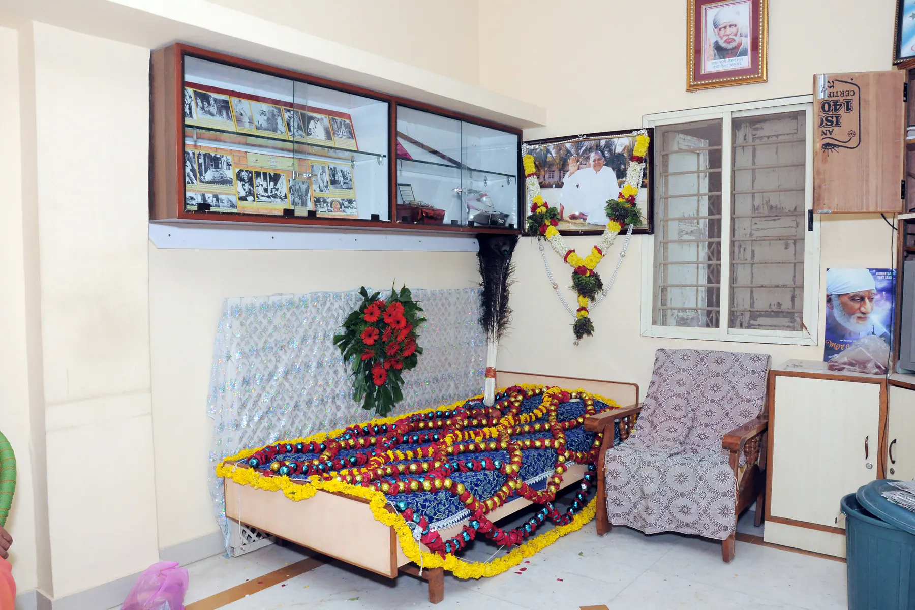 Gurusthan corner with decorated Samadhi Sthal, framed photographs, and a chair