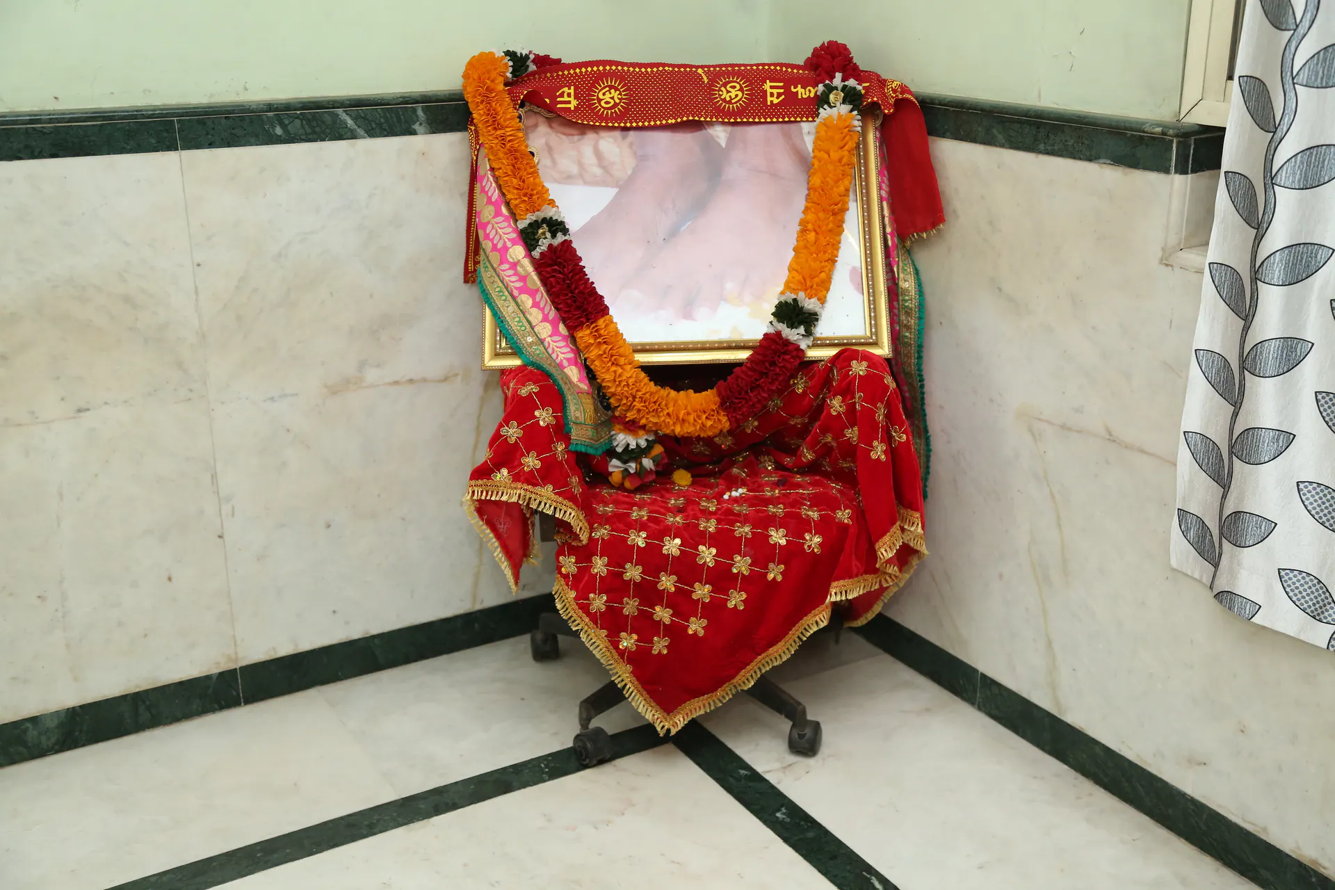 Decorated chair with framed paduka photograph and garlands inside Gurusthan