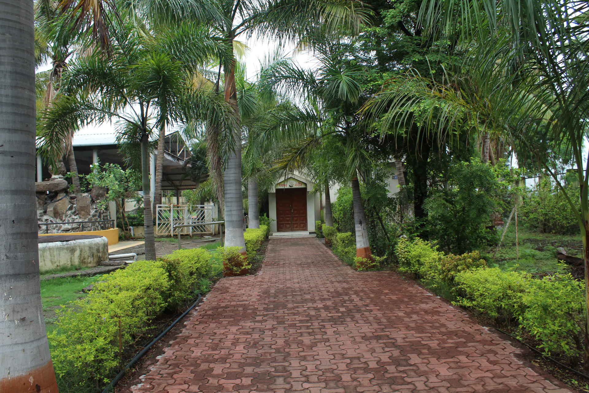 Brick pathway through the Saidham Mandir garden toward a small shrine